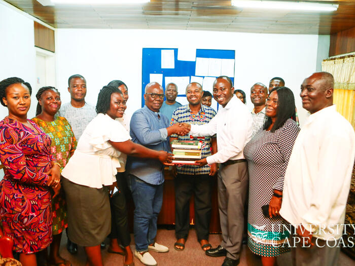 Prof. Emmanuel Amo Ofori handing the books to the representatives of the department Group of people handing over books